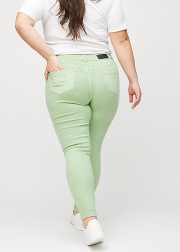Light green skinny jeans seen from the back on a plus-size model, so the entire product can be seen.