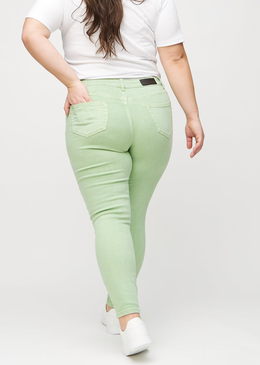 Light green skinny jeans seen from the back on a plus-size model, so the entire product can be seen.