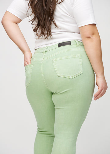 Light green skinny jeans seen from the back up close on a plus-size model to show details.