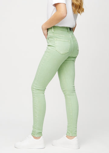 Light green skinny jeans seen from the side on a model.