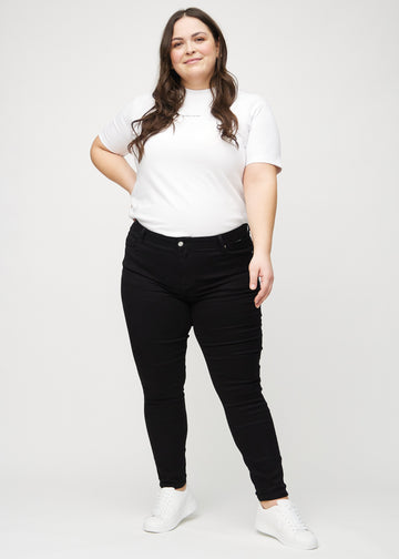 Skinny jeans for women in black, color Ravens. Full-length view of a plus-size model wearing the jeans.