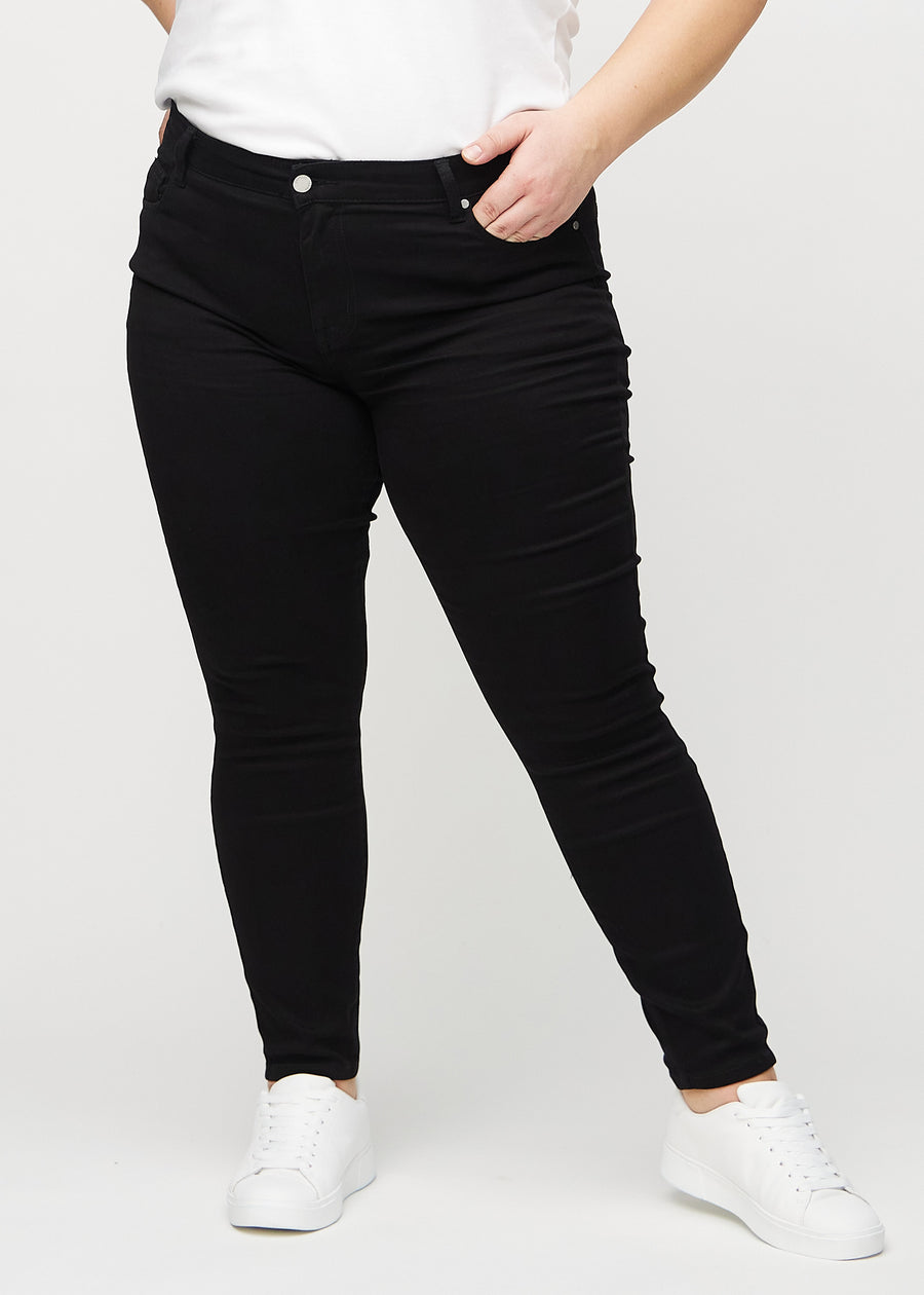 Skinny jeans for women in black, color Ravens. Front view on a plus-size model, showing the close fit through the legs.