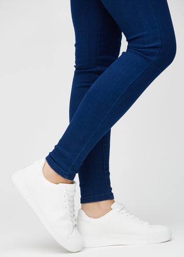 Skinny jeans for women in dark blue, color Royals. Close-up at the ankles on a model, showing the close-fitting leg openings.