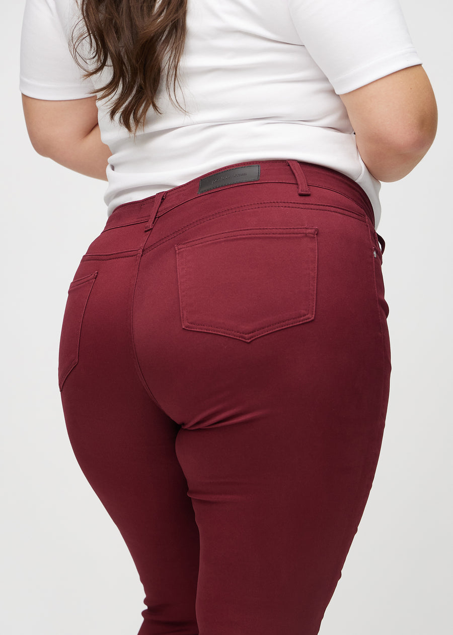 Skinny jeans for women in dark red, color Santas. Close-up back view on a plus-size model, showing details.