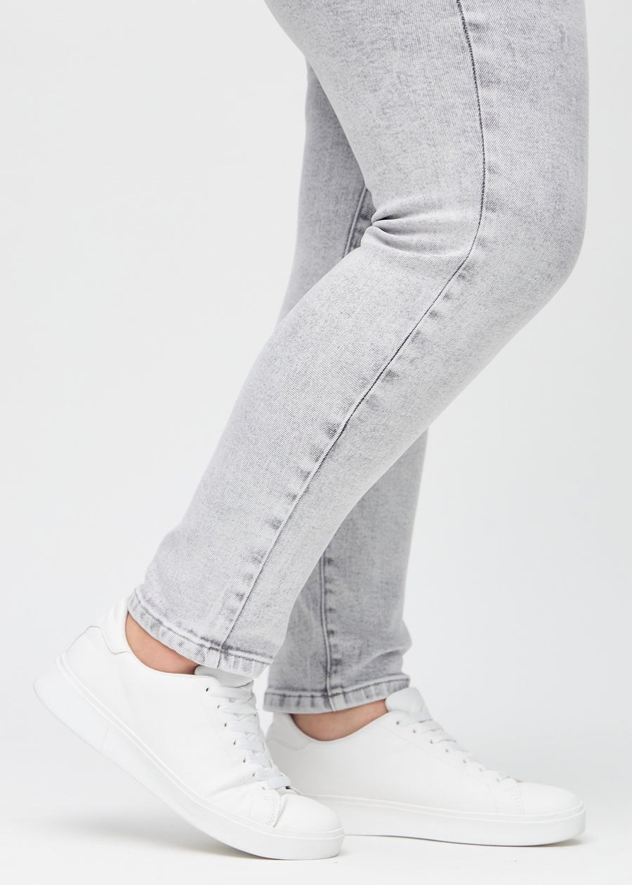 Slim jeans for women in light grey, color Ashes. Close-up at the ankles on a plus-size model, showing the fit at the leg openings.