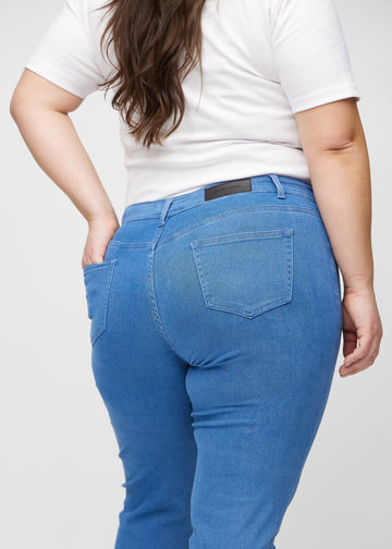 Slim jeans for women in blue, color Geraniums. Close-up back view on a plus-size model, showing the details.