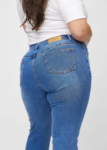 Slim jeans for women in blue, color Rivers. Close-up back view on a plus-size model, showing the details.