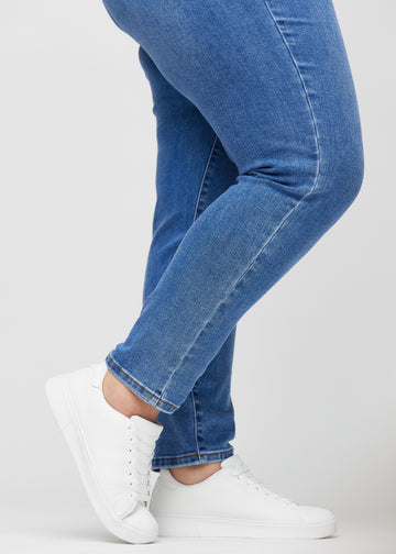 Slim jeans for women in blue, color Rivers. Close-up at the ankles on a plus-size model, showing the fit at the leg openings.