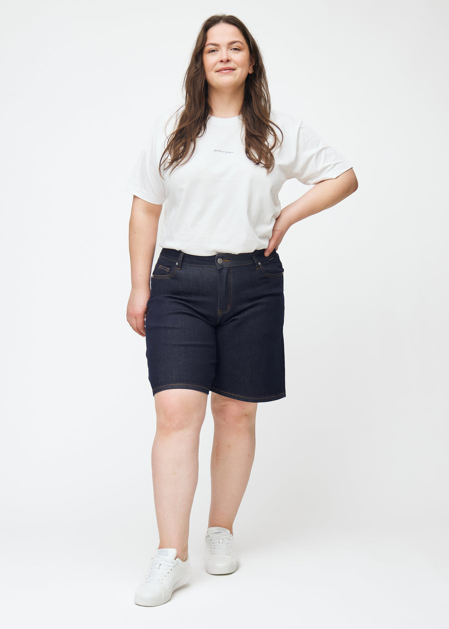 Full image of a plus-size model wearing deep dark blue denim shorts for women in the colour Midnights with a loose fit.