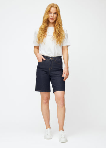 Full image of a model wearing deep dark blue denim shorts for women in the colour Midnights with a loose fit.
