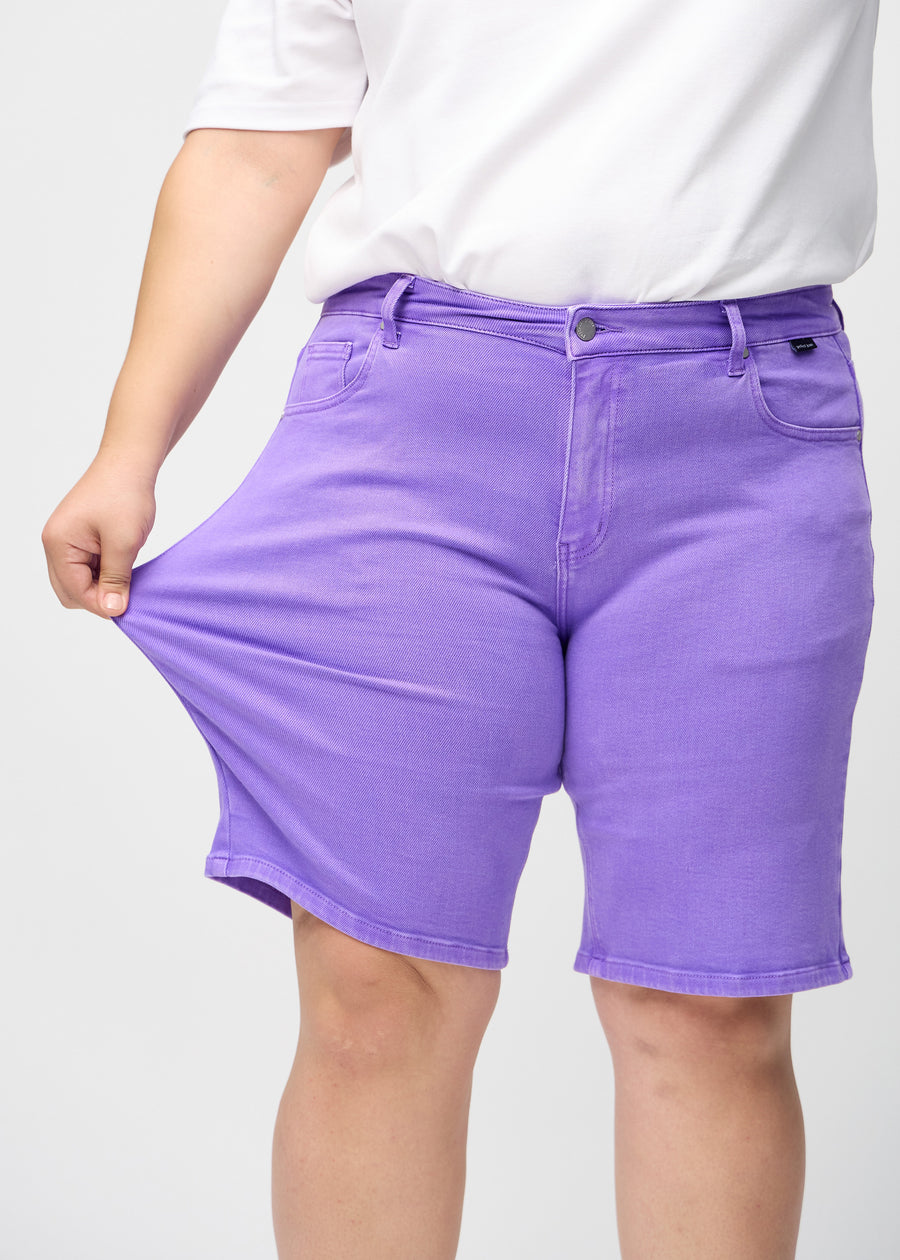 Plus-size model stretches the shorts at the thigh to show the stretch.