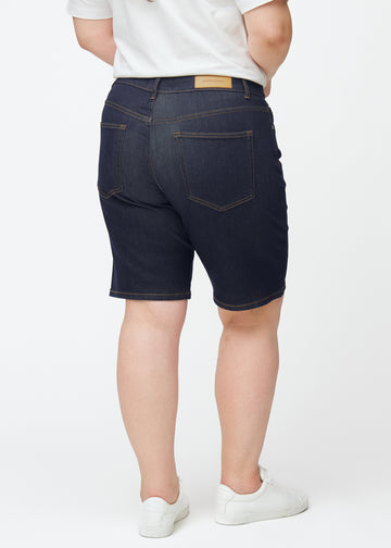 Deep dark blue denim shorts for women in the colour Midnights seen from the back on a plus-size model.