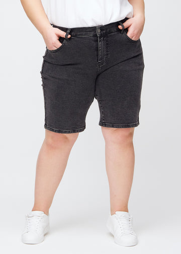 Dark grey denim regular middle shorts, model name Shadows, which fall straight down the leg and end just above the knee on a plus-size model, seen from the front.
