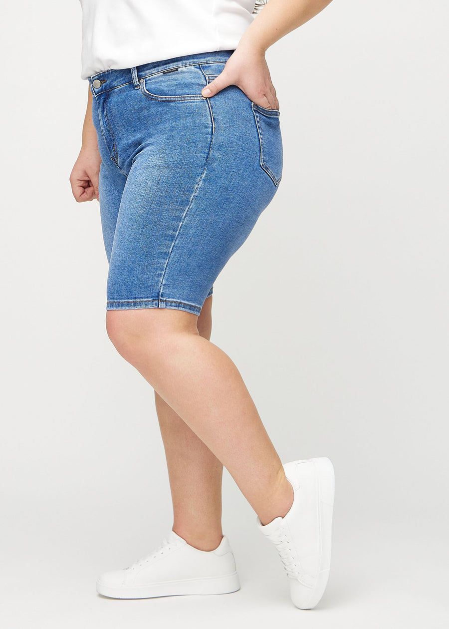 Denim skinny middle shorts seen from the side on a plus-size model.