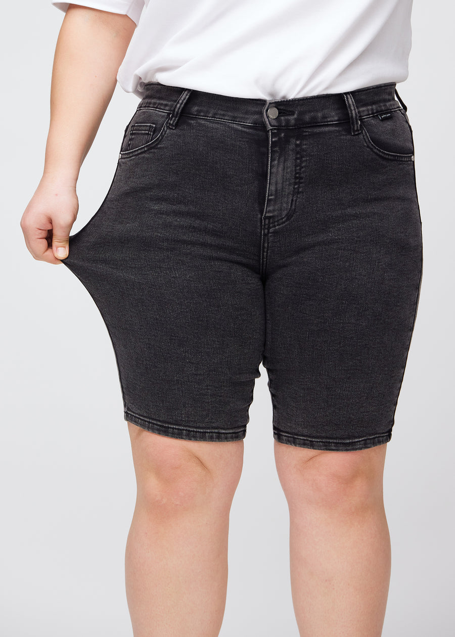 Plus-size model stretches the shorts at the thigh to show the stretch.
