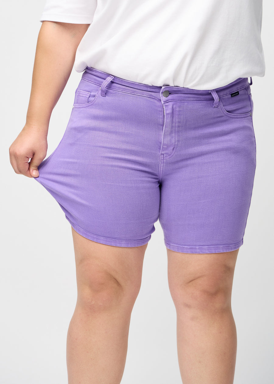 The plus-size model stretches the shorts at the thigh to show the stretch.