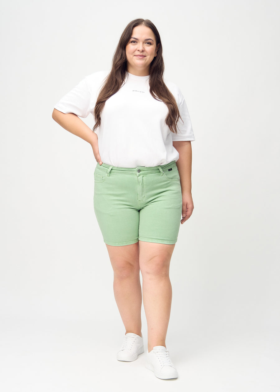 Full image of a plus-size model in light green skinny short shorts.