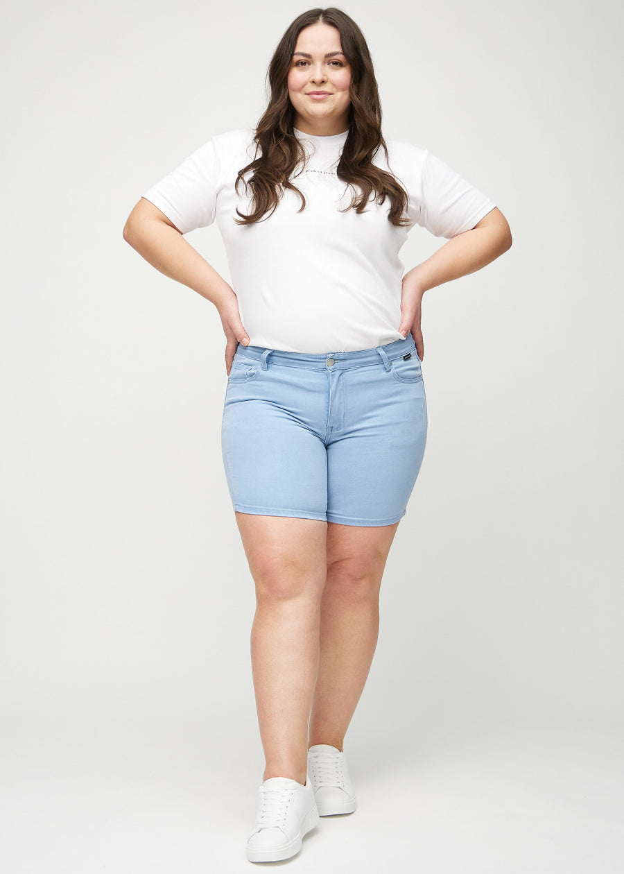 Full image of a plus-size model in light blue skinny short shorts.