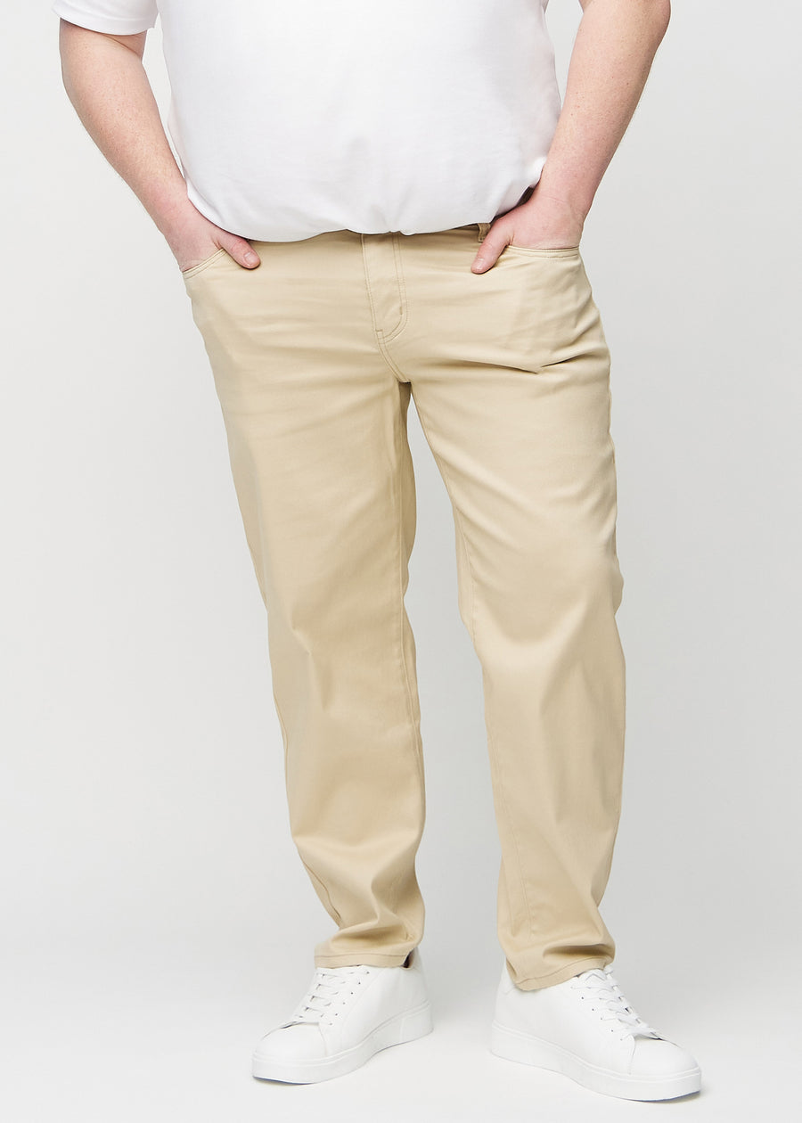 Beige regular jeans, model name Gazelles, which goes straight down the leg on a plus-size model, seen from the front.