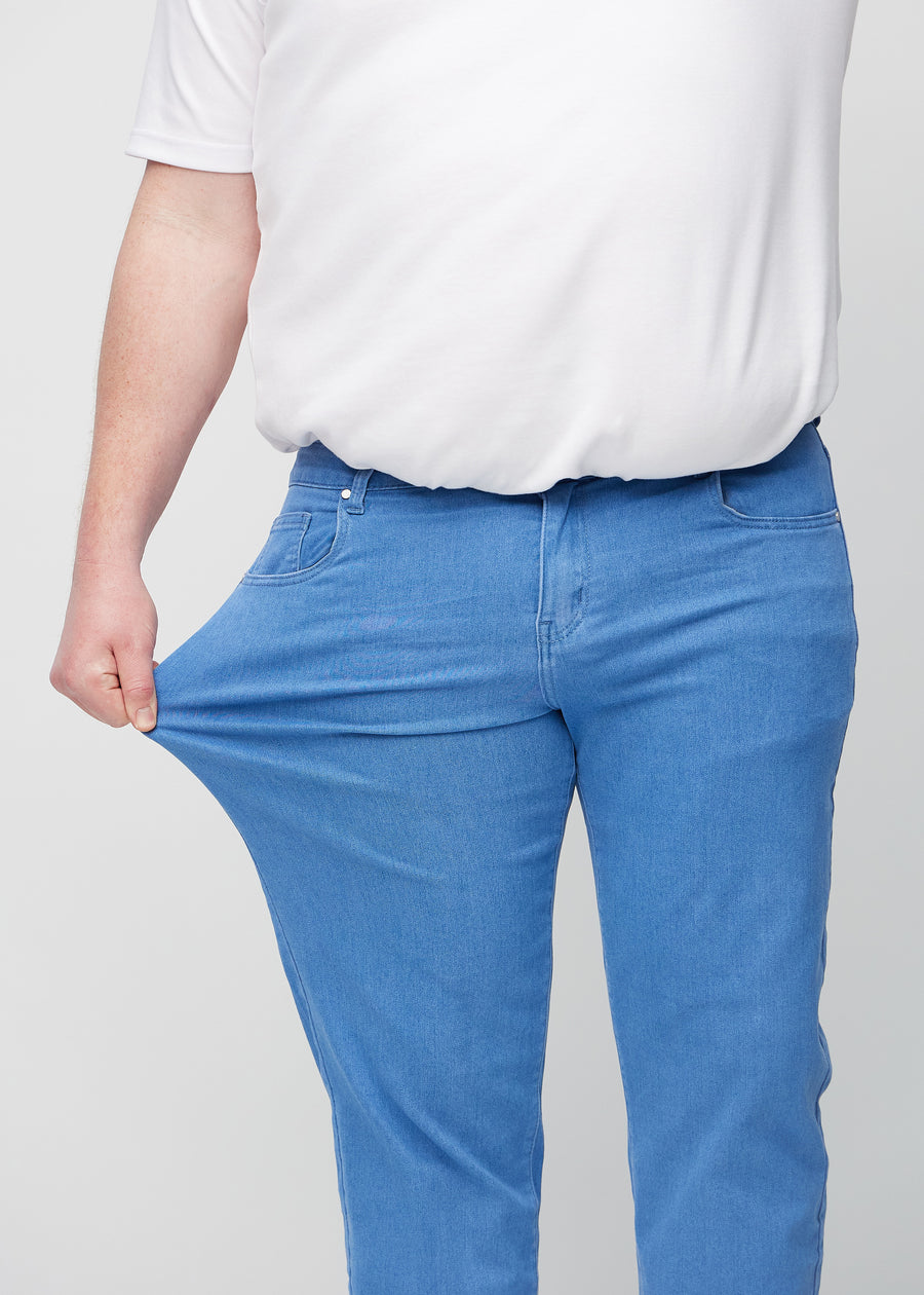 The plus-size model stretches the jeans at the thigh to show the stretch.