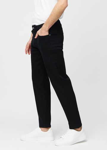 Black regular jeans seen from the side on a model.