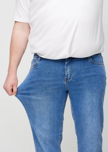 The plus-size model stretches the jeans at the thigh to show the stretch.