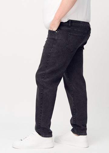 Dark grey denim regular jeans viewed from the side on a plus-size model.