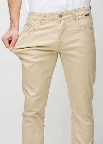 Model stretches the jeans at the thigh to show the fabric&