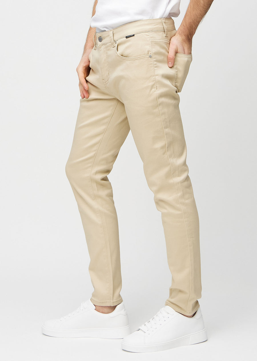 Beige slim jeans viewed from the side on a model.