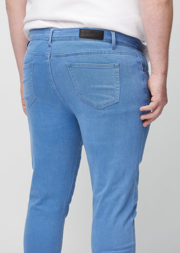 Close-up back view of blue slim jeans on a plus-size model showing details.