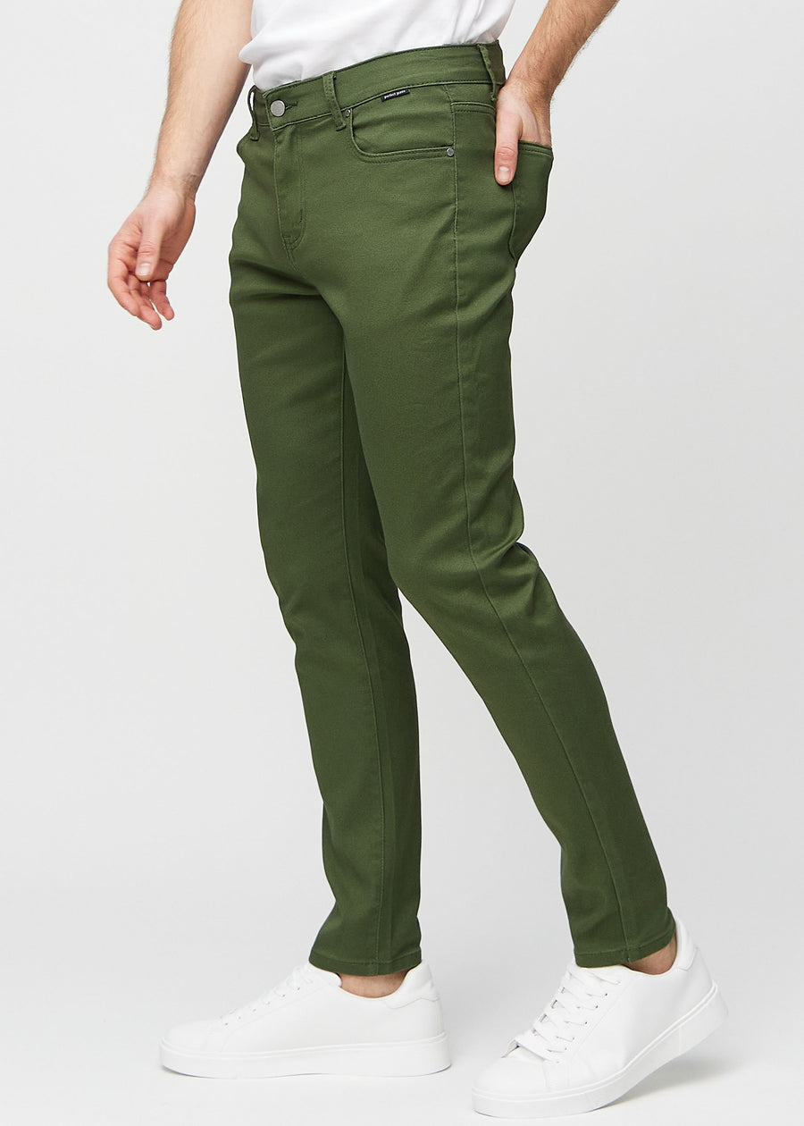 Dark green slim jeans viewed from the side on a model.