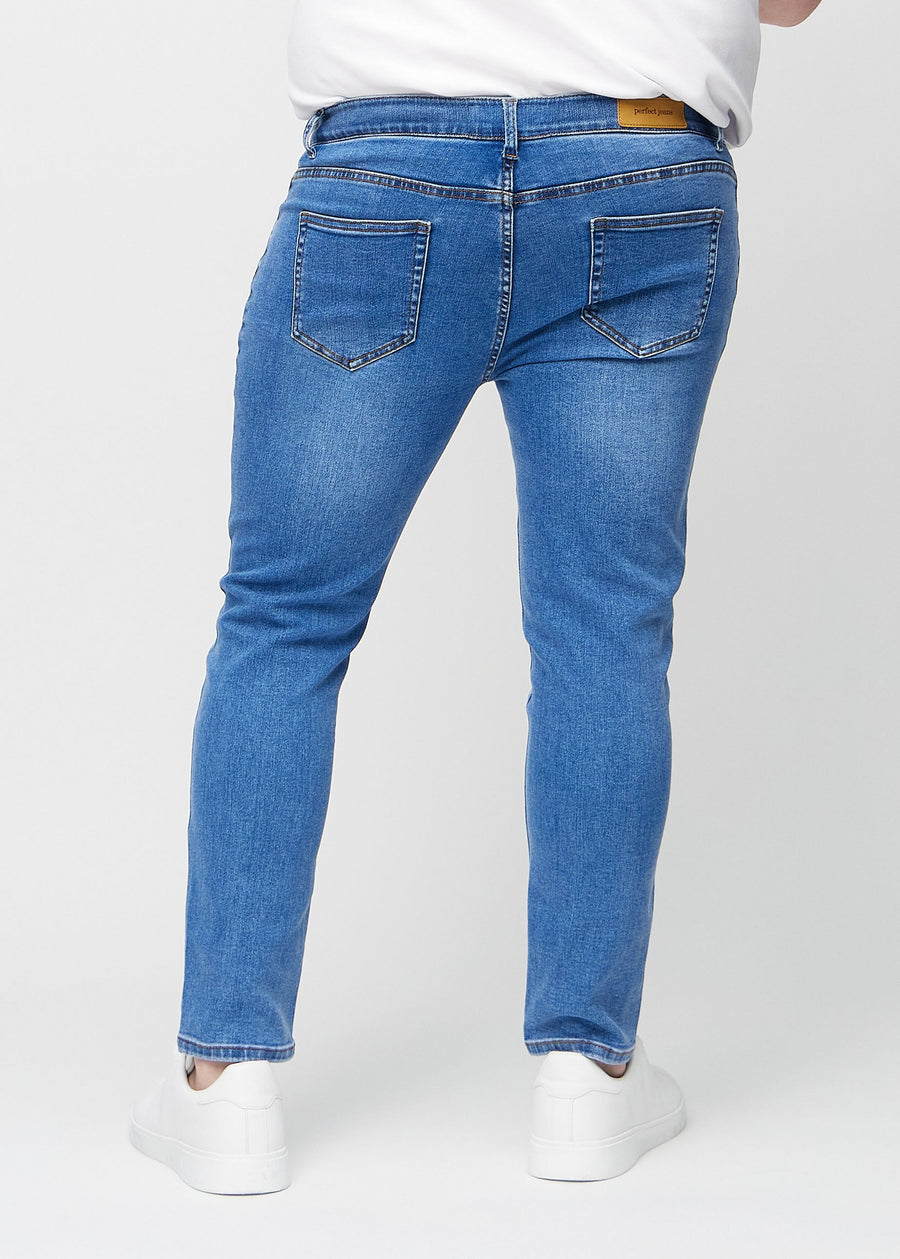 Blue denim slim jeans viewed from the back on a plus-size model to show the full product.