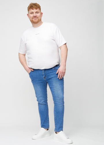 Full-length view of a plus-size model in blue denim slim jeans.