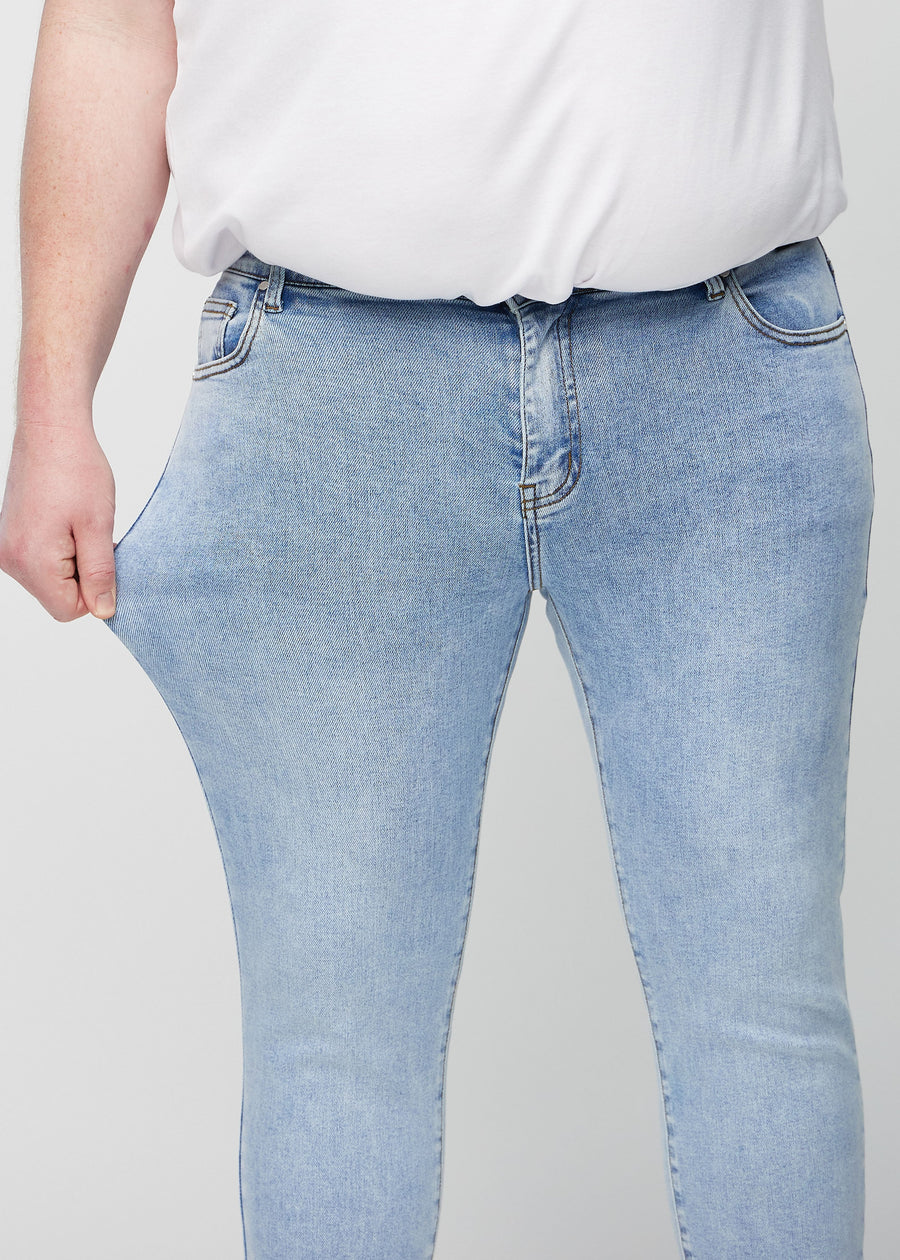 Plus-size model stretches the jeans at the thigh to show the fabric&