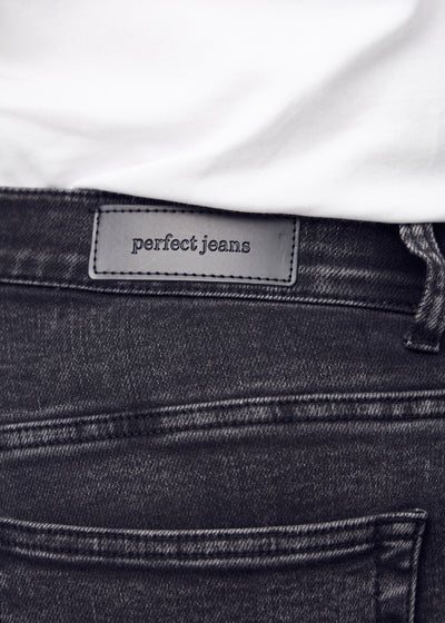 Baglommen på et par mørkegrå denim slim capris set tæt på – tydeligt logo og tekstur vist på en plus-size model.