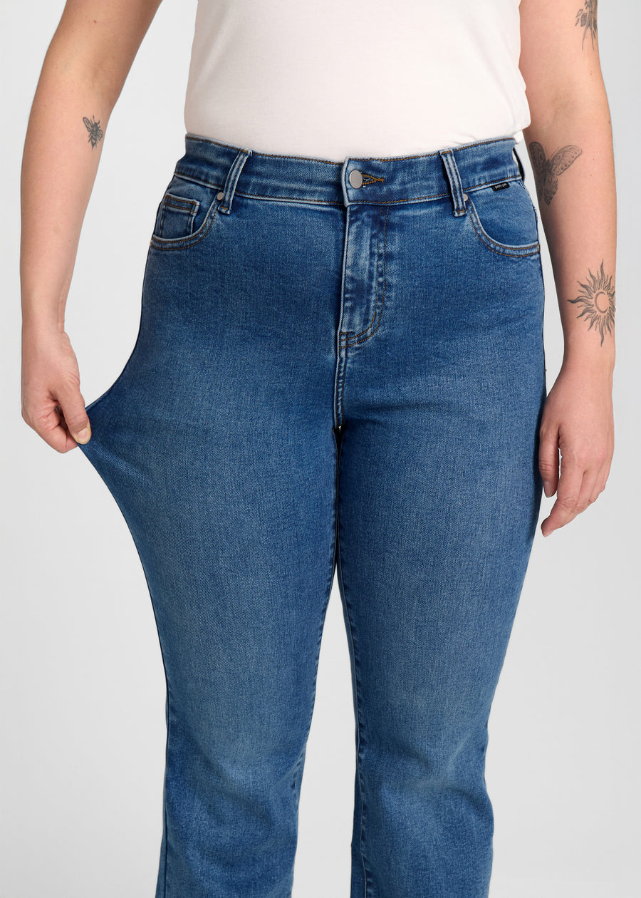 Model strækker jeansene ved låret for at vise stretch.