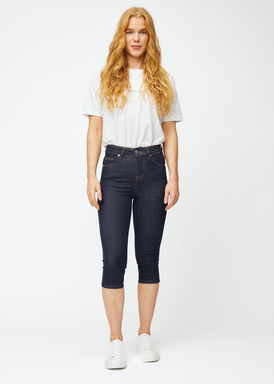 Model viser dyb mørkeblå denim capris til kvinder i farven Midnights med skinny pasform i bevægelse.